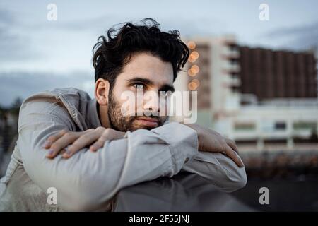 Uomo d'affari con le braccia incrociate appoggiate sulla ringhiera Foto Stock