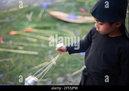 Un ragazzo guatemalteco che cammina con incenso durante una processione durante la settimana Santa ad Antigua, Guatemala. Foto Stock