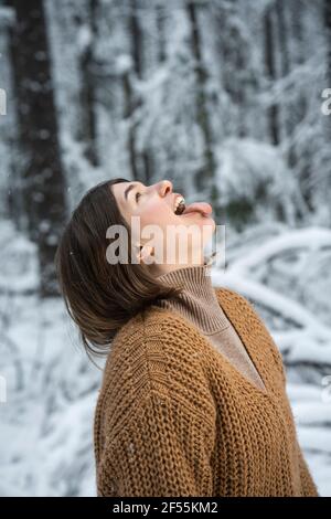 Donna giocosa che si stacca la lingua mentre si trova in piedi nella foresta Foto Stock