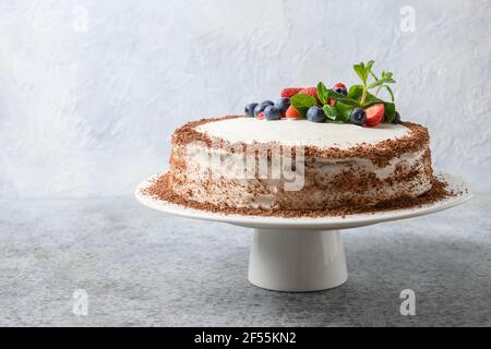 Gustosa torta fatta in casa di mascarpone e biscotto decorato frutti di bosco, menta, fragole e mirtilli. Foto Stock