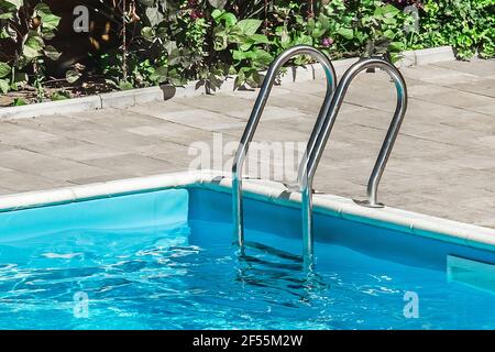 Corrimano di sicurezza vicino alla piscina, acqua blu all'aperto, primo piano. Foto Stock