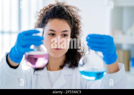 Medico femminile che esamina la soluzione chimica in becher in laboratorio Foto Stock