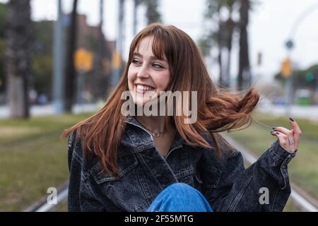 Donna allegra con capelli castani che guardano via Foto Stock