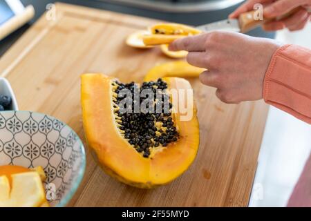 Donna che taglia la papaia in cucina a casa Foto Stock