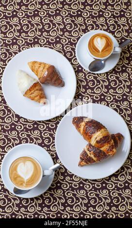 Due colazioni al caffè con tre tipi di croissant in un sfondo della tabella Foto Stock