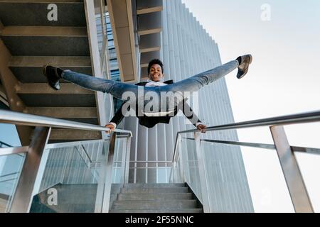 Felice maschio professionista che fa spaccature su ringhiera scala Foto Stock