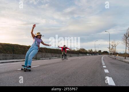 Le amiche si divertono mentre guidano i pattini sulla strada Foto Stock