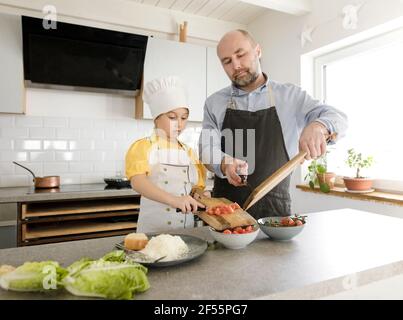 Figlia e padre preparano il cibo mentre si trovano in cucina a casa Foto Stock