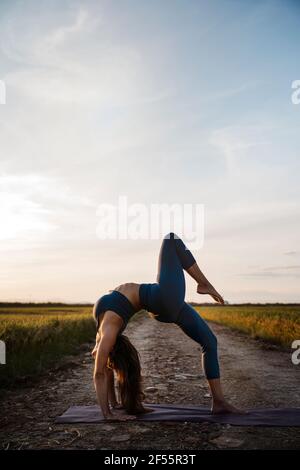 Donna che si piega indietro mentre pratica yoga Foto Stock