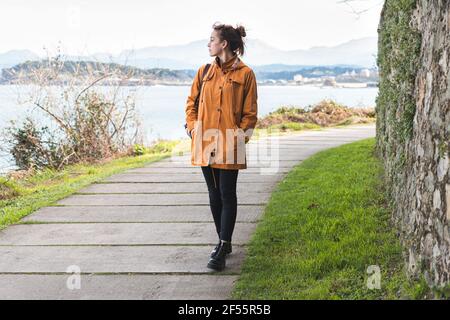 Giovane donna che cammina da sola lungo la passeggiata costiera della baia di Biscaglia Foto Stock