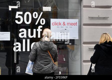 Monaco, Germania. 23 marzo 2021. Foto oggetto: Shopping, Shopping Clicca e incontra a Monaco, appuntamento shopping, accesso e shopping dopo aver fatto un appuntamento, i clienti sono autorizzati a fare acquisti nel negozio. Appuntamenti, registrati. Un cartello appende di fronte a un negozio a Muenchen con l'avviso di fissare un appuntamento online-due donne stand di fronte a una vetrina e guardare in un negozio. sconto del 50%, sconti, sconti. | utilizzo in tutto il mondo credito: dpa/Alamy Live News Foto Stock