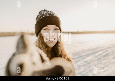 Ritratto di bella ragazza teenage che indossa cappello a maglia che raggiunge verso fotocamera Foto Stock