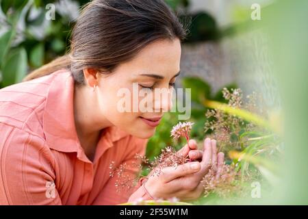 Giovane donna che annuisce fiori freschi in giardino Foto Stock