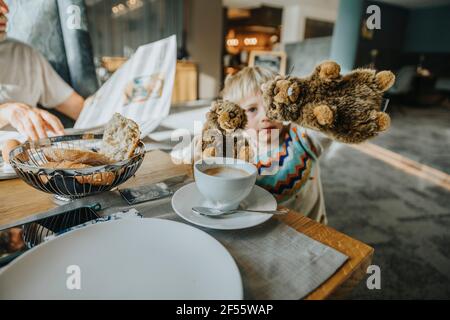 Ragazzo che mostra il giocattolo delle marmotte alpine al tavolo in camera d'albergo Foto Stock