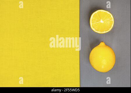 Colore trendy dell'anno 2021. Giallo luminoso e grigio estremo. Frutta al limone su fondo grigio, piatto. Foto Stock