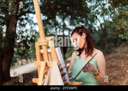 Giovane artista donna pittura su cavalletto Foto Stock