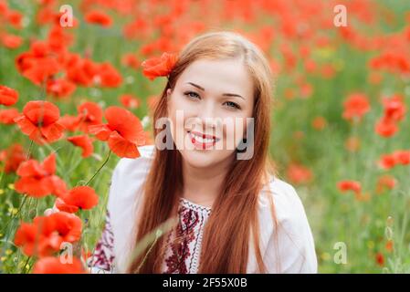 Ucraino bella Donna in ricamo tradizionale in campo papaveri ritratto esterno. Raccolta papaveri e fiore di mais in campo estivo. Pop in fiore Foto Stock