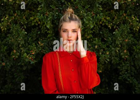 Bella donna in camicia rossa con testa in piedi a mano contro piante Foto Stock