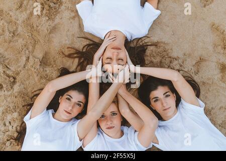 Le giovani donne che toccano l'amica mentre si sdraiano sulla sabbia durante fine settimana Foto Stock