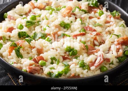 Cucina Veneziana Risi e Bisi di riso con piselli e fette di prosciutto primo piano in un piatto sul tavolo. Orizzontale Foto Stock