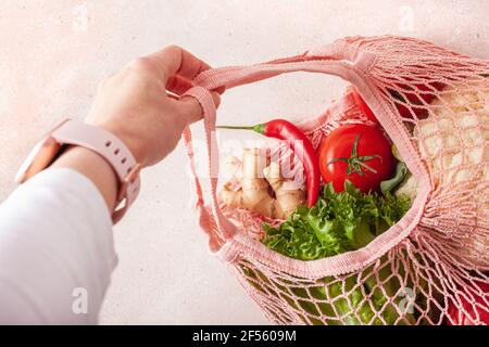 la mano tiene le verdure di frutta in sacchetto di cotone a rete riutilizzabile, concetto di rifiuto zero senza plastica Foto Stock