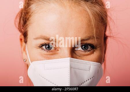 Primo piano di una donna che indossa una maschera protettiva contro lo sfondo colorato Foto Stock