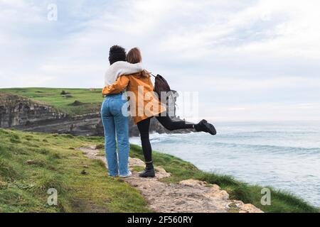 Giovani amici femminili in piedi con le braccia intorno a. Acantilado El Bolao Foto Stock