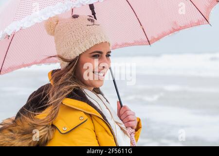 Ritratto di giovane donna in piedi all'aperto con ombrello in mano Foto Stock