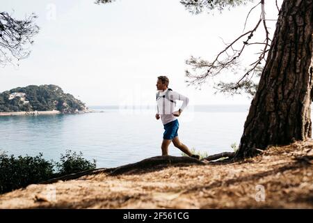 Uomo maturo che corre contro il cielo limpido Foto Stock