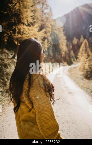 Giovane donna che indossa una giacca che guarda il percorso nella foresta Foto Stock
