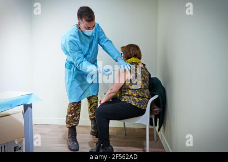 Un medico inocula una donna con il vaccino AstraZeneca COVID-19 hotspot presidiato da personale medico dell'esercito. Torino, Italia - Marzo 2021 Foto Stock