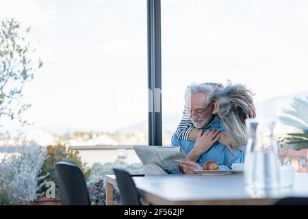 Donna anziana romanting con l'uomo mentre si sta in piedi dalla finestra a. casa Foto Stock