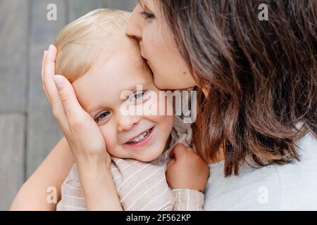 Primo piano di madre abbracciando e baciando il suo figliolo Foto Stock