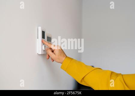 Donna matura che regola il termostato a casa Foto Stock