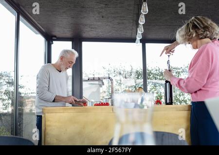 Coppia senior che lavora mentre si trova in cucina a casa Foto Stock