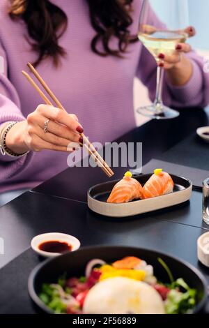 Donna matura che ha sushi con chopsticks al ristorante Foto Stock