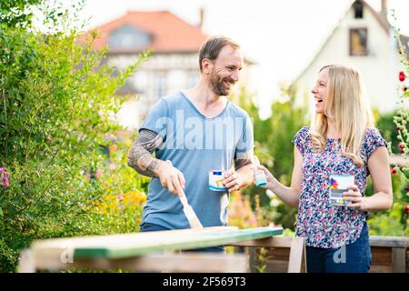 Coppia matura ridendo mentre dipingendo in giardino Foto Stock