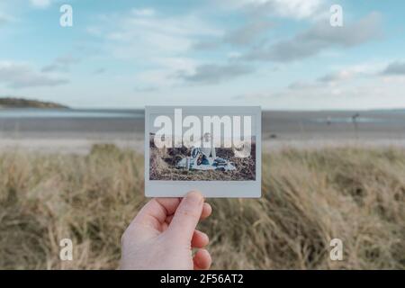 Fotografia istantanea in spiaggia con la mano Foto Stock