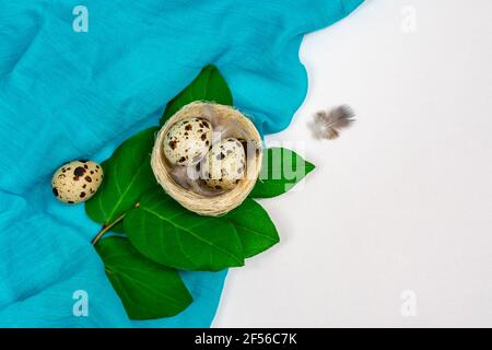 Layout pasquale con uova di quaglia in un nido d'uccello con un panno. Luogo per un'iscrizione. Vista dall'alto. Decorazioni primaverili di Pasqua. Foto Stock