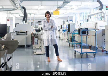 Fidato ingegnere femminile con braccia incrociate in piedi nel settore Foto Stock