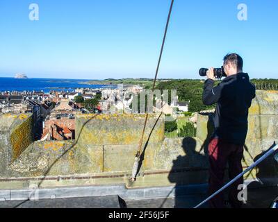 Uomo che scatta fotografie dalla cima della torre della chiesa di St Andrew Blackadder, a nord di Berwick Foto Stock