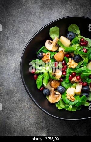 Insalata autunnale composta da lattuga di agnello, funghi, pere fritte, mirtilli, semi di melograno e noci Foto Stock