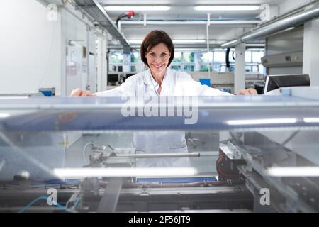 Sorridente tecnico femminile da macchinari nell'industria Foto Stock