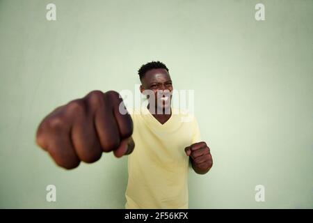 Ritratto grandangolare di giovane uomo africano aggressivo con cui pugno fist Foto Stock