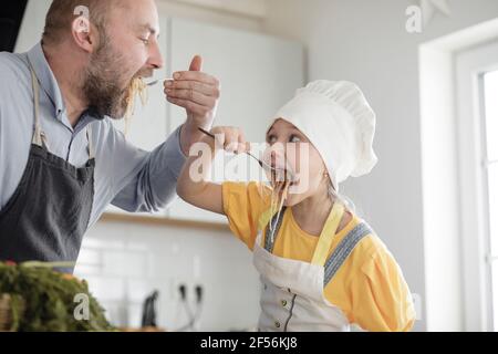 Padre e figlia mangiano cibo mentre si trovano in cucina a casa Foto Stock