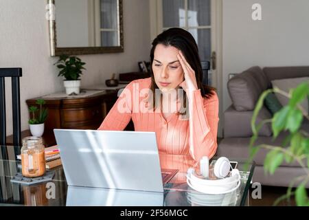 Preoccupata imprenditore femminile che lavora su un computer portatile a casa Foto Stock