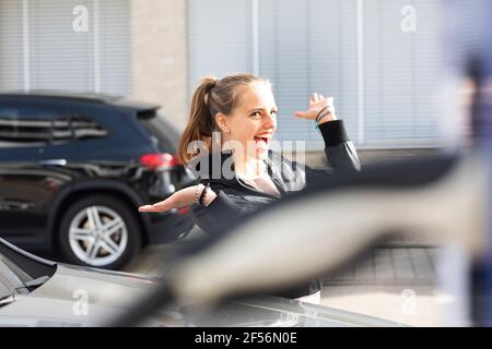 Ritratto di giovane bella bionda in piedi all'aperto e sorridente con bracci sollevati Foto Stock