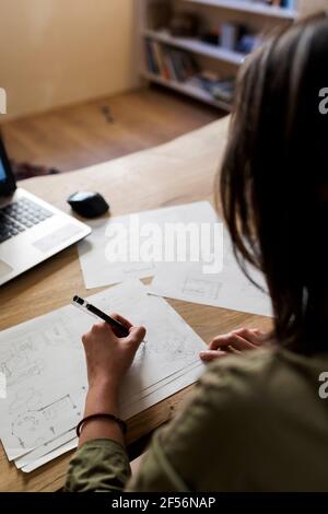 Femminile design professionale che fa disegno su carta alla scrivania in officina Foto Stock