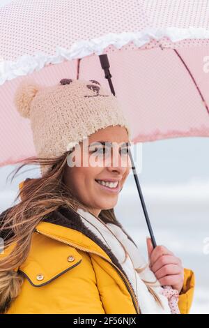 Ritratto di giovane donna in piedi all'aperto con ombrello in mano Foto Stock