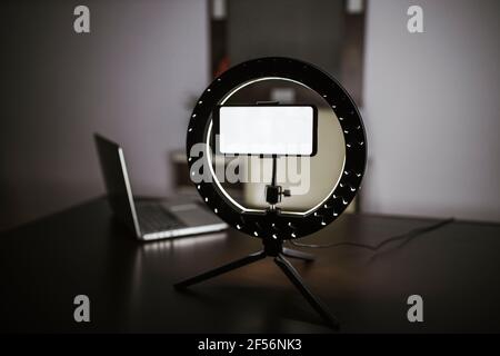 Smartphone illuminato su cavalletto con illuminatore anulare a LED sul tavolo Foto Stock